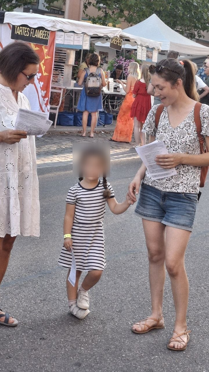 Une membre du collectif distribue un tract à une passante lors du corso fleuri de Sélestat