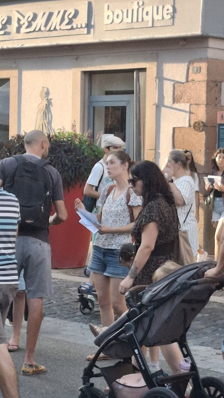 Une passante tient un tract distribué par le collectif au corso fleuri de Sélestat