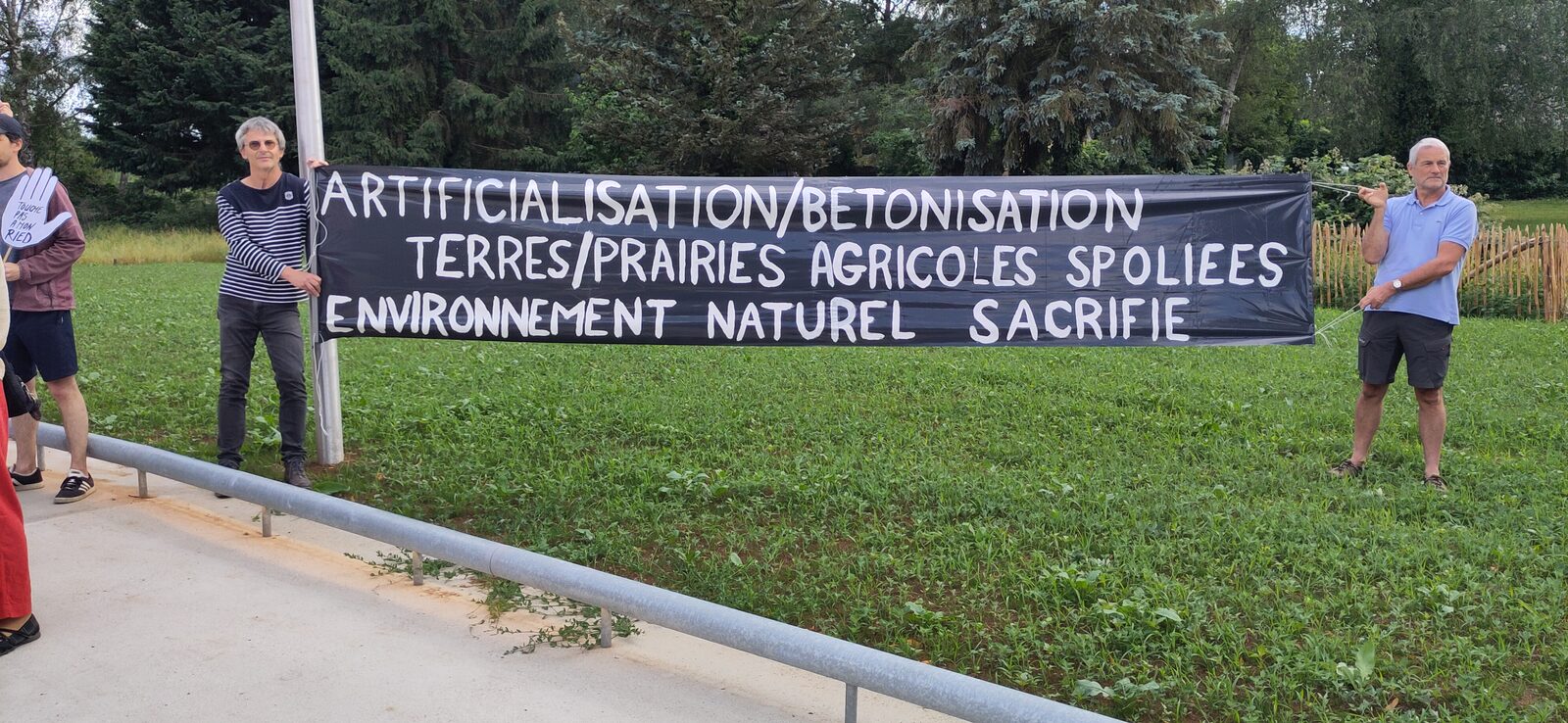 Deux membres du collectif tiennent la banderole « Terres et prairies agricoles spoliées, environnement naturel sacrifié »