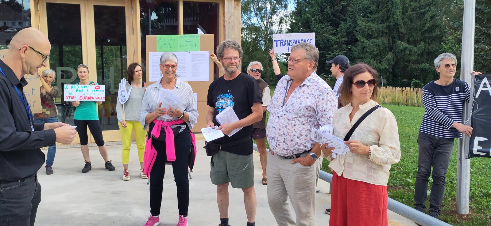 Membres du collectif avec leurs pancartes devant l'Espace du Ried à Benfeld